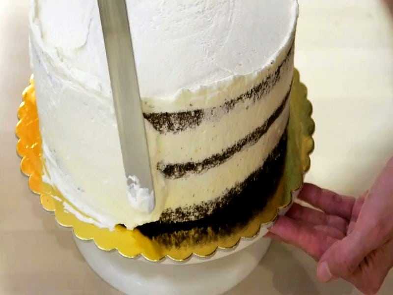 Промажьте бока торта первым тонким слоем крема